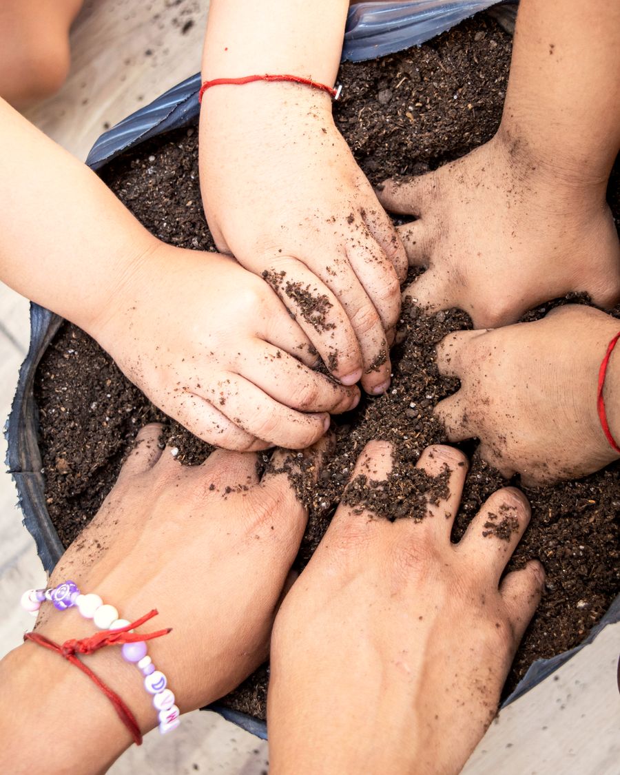 Niños y niñas de Tenvilú explorando la tierra en el jardín